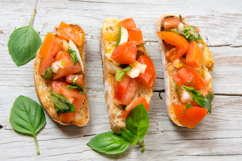 three slices of bruschetta with tomatoes and basil leaves